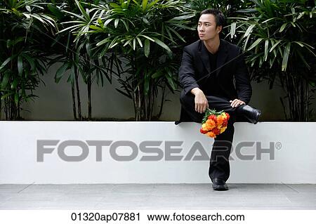 A man sits down and waits while he holds a bunch of flowers View Large Photo Image Stock Image - A man sits down and waits while he holds a bunch of flowers. Fotosearch