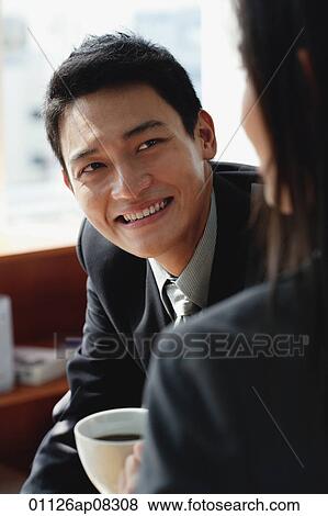 A man smiles as he has coffee with a woman View Large Photo Image Stock Photo - A man smiles as he has coffee with a woman. Fotosearch