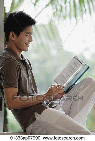 A man smiles as he reads a book View Large Photo Image Stock Image - A man smiles as he reads a book. Fotosearch