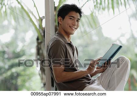A man smiles at the camera as he reads a book View Large Photo Image Stock Image - A man smiles at the camera as he reads a book. Fotosearch