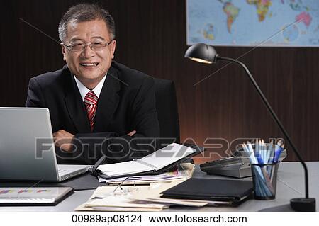 A man smiles at the camera as he sits at his desk View Large Photo Image Picture - A man smiles at the camera as he sits at his desk. Fotosearch