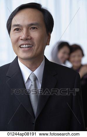 A man smiles while a bride and her mother hug in the background View Large Photo Image Stock Image - A man smiles while a bride and her mother hug in the background. Fotosearch