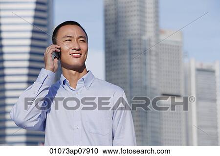 A man talks on his cellphone outdoors View Large Photo Image Stock Image - A man talks on his cellphone outdoors. Fotosearch