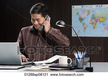 A man talks on the phone as he works View Large Photo Image Stock Image - A man talks on the phone as he works. Fotosearch