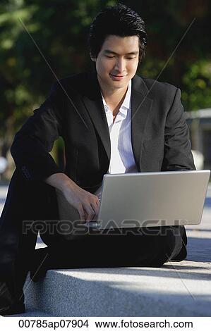 A man uses his laptop in the park View Large Photo Image Picture - A man uses his laptop in the park. Fotosearch