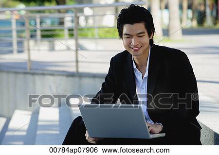 A man uses his laptop outdoors View Large Photo Image Stock Photograph - A man uses his laptop outdoors. Fotosearch