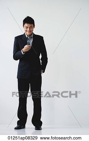 A man wearing a suit smiles as he dials on his cellphone View Large Photo Image Stock Photo - A man wearing a suit smiles as he dials on his cellphone. Fotosearch
