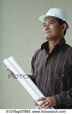 A man with a helmet and rolled up plans View Large Photo Image Stock Image - A man with a helmet and rolled up plans. Fotosearch