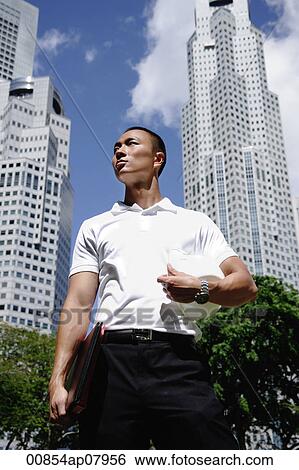 A man with a helmet stands in front of skyscrapers View Large Photo Image Stock Photograph - A man with a helmet stands in front of skyscrapers. Fotosearch