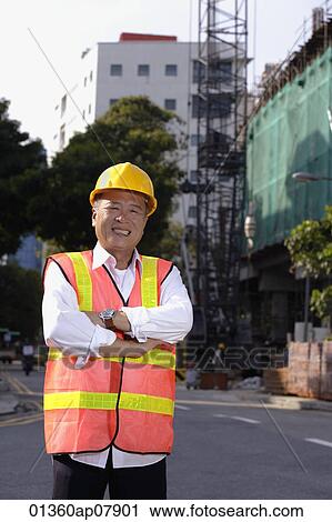 A man with a yellow helmet smiles at the camera, hands crossed View Large Photo Image Stock Image - A man with a yellow helmet smiles at the camera, hands crossed. Fotosearch