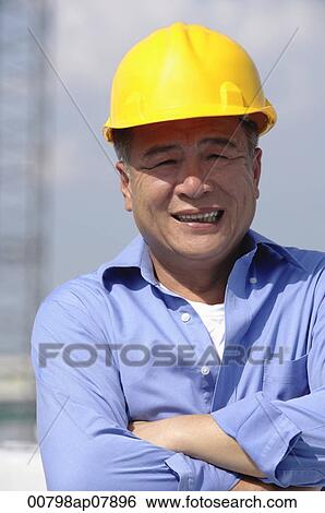 A man with a yellow helmet smiles at the camera View Large Photo Image Stock Photograph - A man with a yellow helmet smiles at the camera. Fotosearch