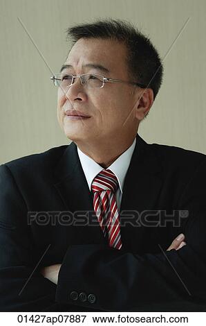 A man with glasses and a suit folds his arms View Large Photo Image Stock Photo - A man with glasses and a suit folds his arms. Fotosearch
