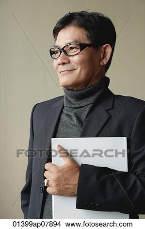 A man with glasses holding a white folder View Large Photo Image Picture - A man with glasses holding a white folder. Fotosearch