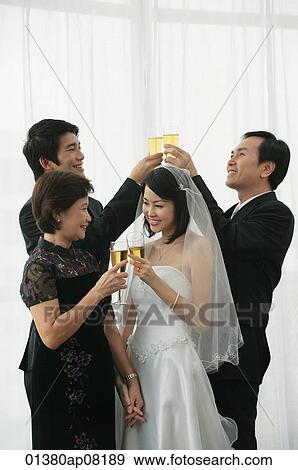 Stock Photo - A newlywed couple and their family raise their glasses for a toast. Fotosearch