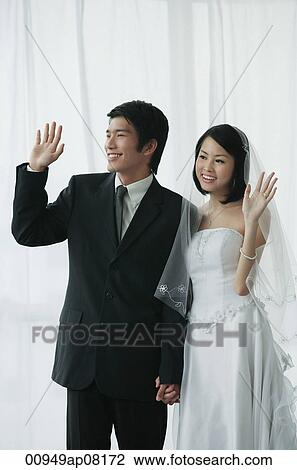 A newlywed couple hold hands and wave View Large Photo Image Stock Image - A newlywed couple hold hands and wave. Fotosearch