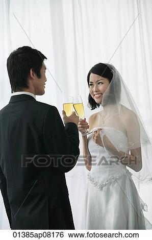 A newlywed couple hold out their champagne glasses for a toast View Large Photo Image Stock Photograph - A newlywed couple hold out their champagne glasses for a toast. Fotosearch