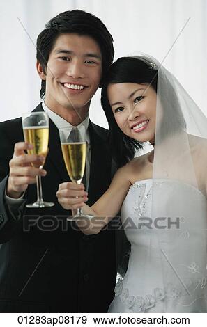 Stock Photo - A newlywed couple smile at the camera. Fotosearch