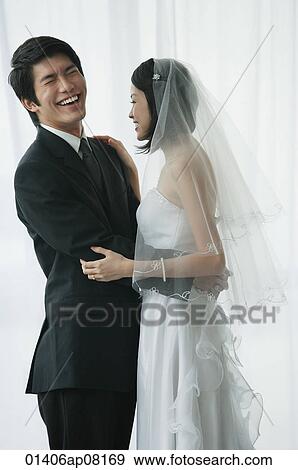 A newlywed couple stand with their arms around each other View Large Photo Image Stock Photo - A newlywed couple stand with their arms around each other. Fotosearch