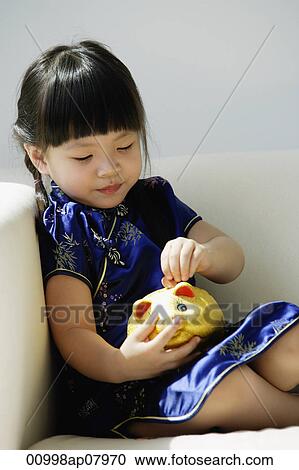 A small girl in blue silk cheongsam plays with a piggy bank View Large Photo Image Stock Image - A small girl in blue silk cheongsam plays with a piggy bank. Fotosearch