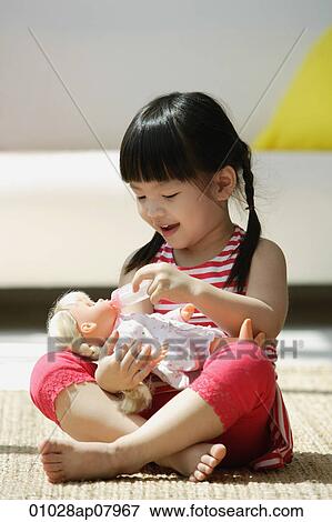 A small girl plays with a doll View Large Photo Image Stock Photo - A small girl plays with a doll. Fotosearch