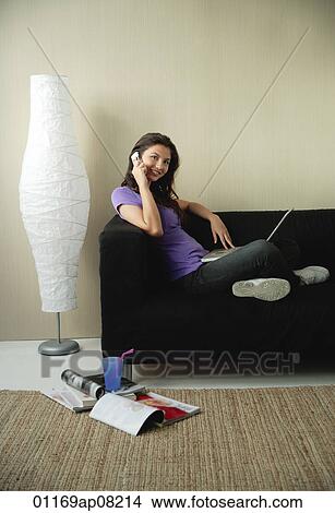 A teenage girl sits on the couch and talks on the phone View Large Photo Image Picture - A teenage girl sits on the couch and talks on the phone. Fotosearch