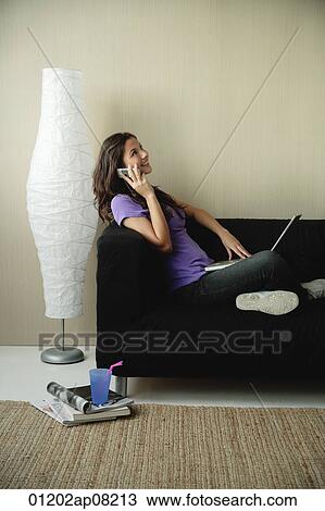 A teenage girl sits on the couch and talks on the phone View Large Photo Image Stock Image - A teenage girl sits on the couch and talks on the phone. Fotosearch