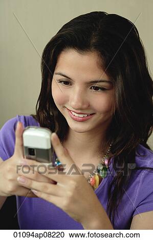 A teenage girl smiles as she uses her cellphone View Large Photo Image Stock Image - A teenage girl smiles as she uses her cellphone. Fotosearch