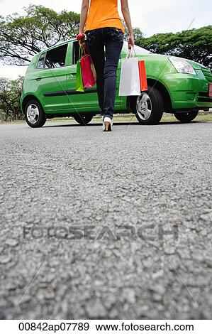 A woman carries shopping bags from her car View Large Photo Image Stock Photo - A woman carries shopping bags from her car. Fotosearch