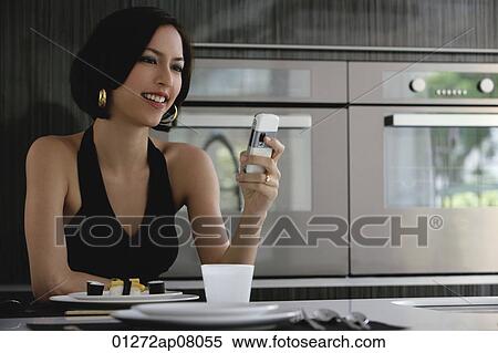 A woman checks her cellphone as she has dinner View Large Photo Image Stock Photography - A woman checks her cellphone as she has dinner. Fotosearch