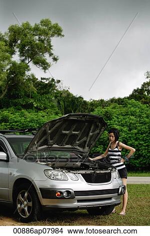 A woman checks under the hood of her car View Large Photo Image Picture - A woman checks under the hood of her car. Fotosearch