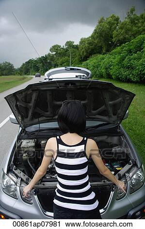 A woman checks under the hood of her car View Large Photo Image Stock Image - A woman checks under the hood of her car. Fotosearch