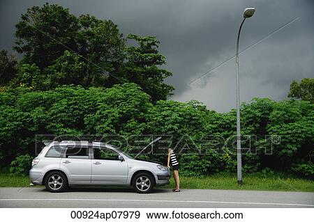 A woman checks under the hood of her car View Large Photo Image Stock Photo - A woman checks under the hood of her car. Fotosearch