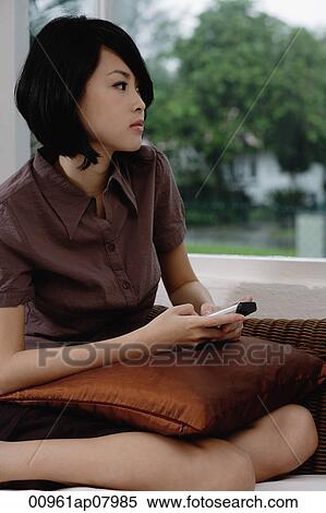 A woman holds a cellphone as she looks out the window View Large Photo Image Stock Photography - A woman holds a cellphone as she looks out the window. Fotosearch