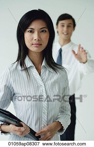 A woman looks at the camera as her colleague tries to get her attention View Large Photo Image Stock Photo - A woman looks at the camera as her colleague tries to get her attention. Fotosearch