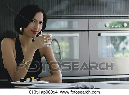 A woman looks at the camera as she holds a cup View Large Photo Image Picture - A woman looks at the camera as she holds a cup. Fotosearch
