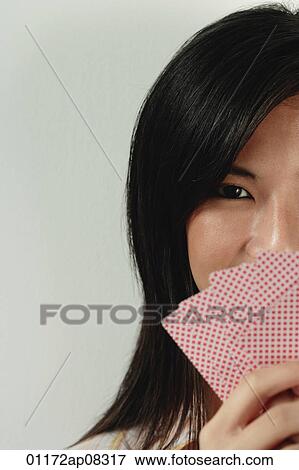 A woman looks at the camera as she holds up a hand of cards View Large Photo Image Stock Photo - A woman looks at the camera as she holds up a hand of cards. Fotosearch