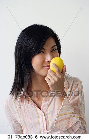 A woman looks at the camera as she holds up a lemon View Large Photo Image Stock Photograph - A woman looks at the camera as she holds up a lemon. Fotosearch