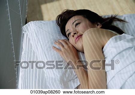A woman looks out the window as she lies in bed View Large Photo Image Stock Image - A woman looks out the window as she lies in bed. Fotosearch