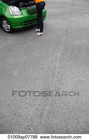 A woman looks under the hood of a car View Large Photo Image Stock Photo - A woman looks under the hood of a car. Fotosearch