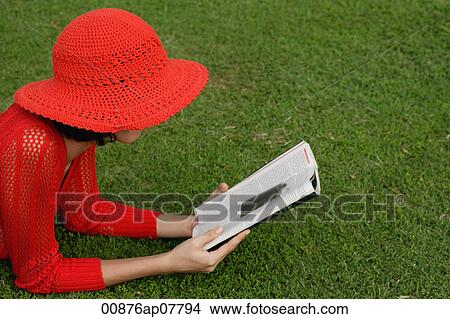 A woman reads while lying on grass View Large Photo Image Picture - A woman reads while lying on grass. Fotosearch