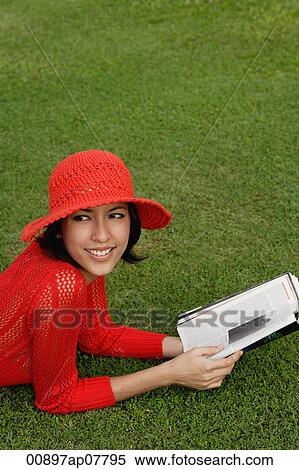 A woman reads while lying on grass View Large Photo Image Stock Photography - A woman reads while lying on grass. Fotosearch