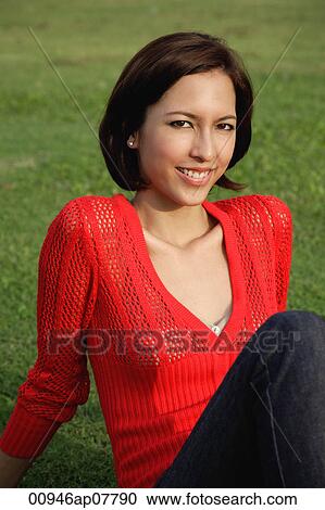 Stock Image - A woman relaxes on grass. Fotosearch