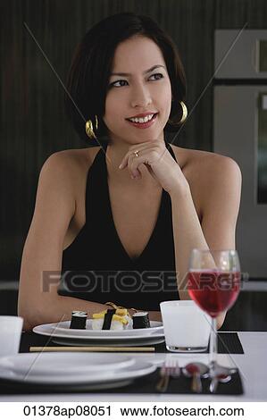 A woman sits at a table with a plate of sushi and a glass of red wine View Large Photo Image Stock Image - A woman sits at a table with a plate of sushi and a glass of red wine. Fotosearch