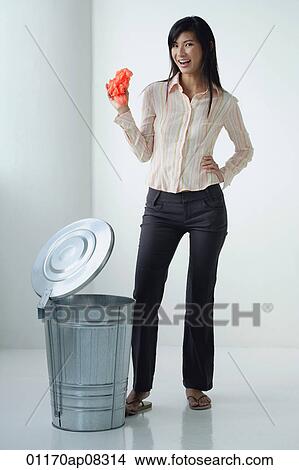 A woman smiles at the camera as she throws something in the rubbish bin View Large Photo Image Picture - A woman smiles at the camera as she throws something in the rubbish bin. Fotosearch