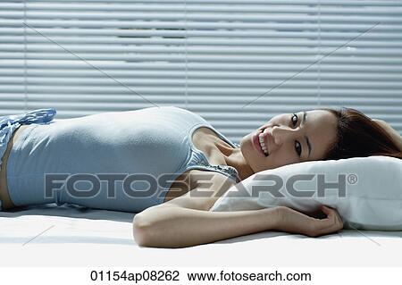 A woman smiles at the camera as she lies in bed View Large Photo Image Stock Image - A woman smiles at the camera as she lies in bed. Fotosearch
