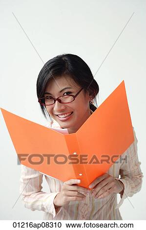 A woman smiles at the camera as she holds an orange folder View Large Photo Image Stock Image - A woman smiles at the camera as she holds an orange folder. Fotosearch
