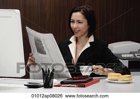A woman takes a break at work and reads the newspaper View Large Photo Image Stock Photograph - A woman takes a break at work and reads the newspaper. Fotosearch
