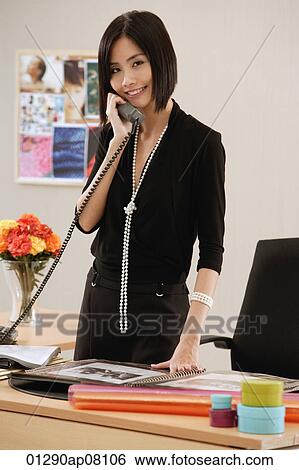 A woman talks on the phone at work View Large Photo Image Stock Photograph - A woman talks on the phone at work. Fotosearch