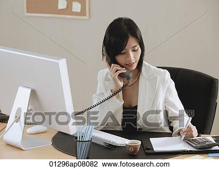 A woman talks on the phone while she is at work View Large Photo Image Stock Image - A woman talks on the phone while she is at work. Fotosearch