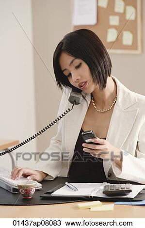 A woman talks on the phone while she is at work View Large Photo Image Stock Image - A woman talks on the phone while she is at work. Fotosearch